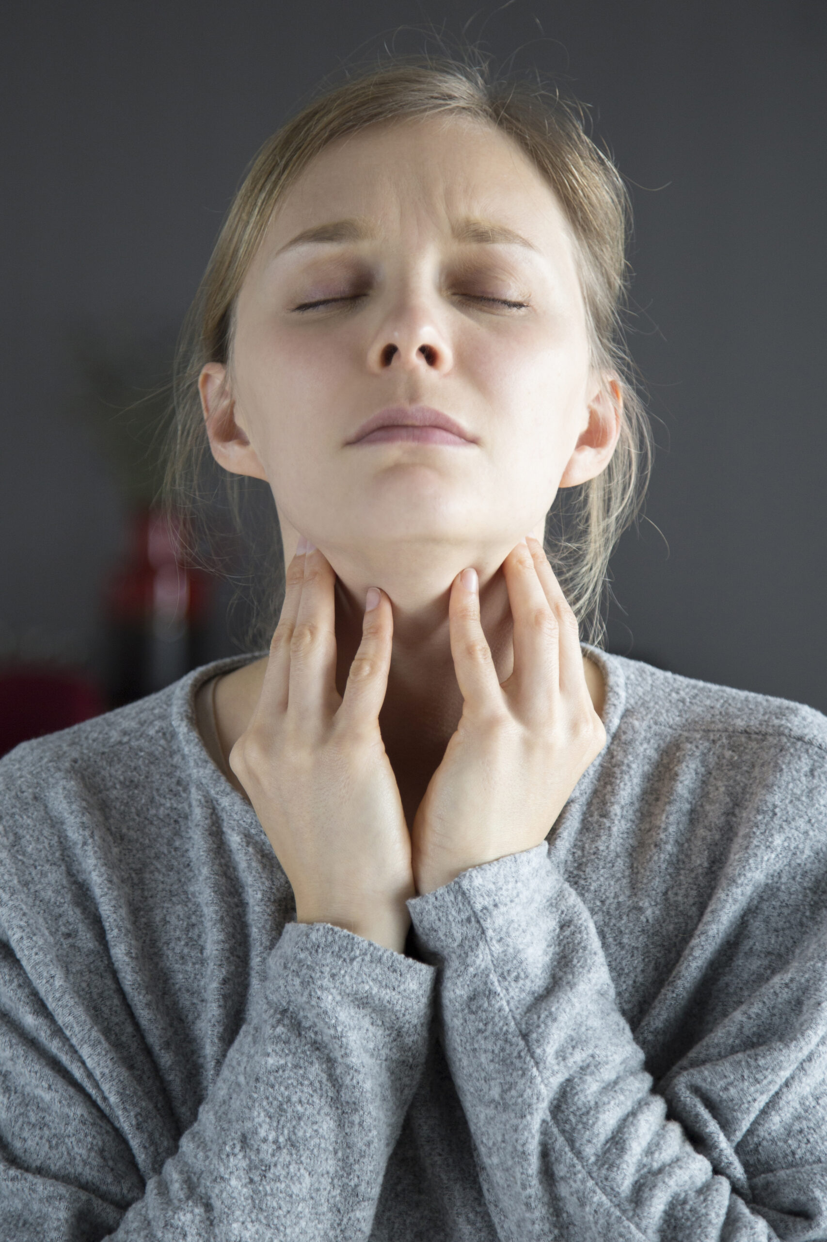 Sick woman with closed eyes having sore throat, touching neck